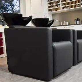 Moderne Friseurwaschbecken mit schwarzen Stühlen in einem hellen Friseursalon.