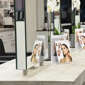 Moderner Friseursalon mit Spiegeln, Kosmetikprodukten und Werbeflyern auf dem Tresen.